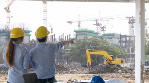 Engineer group and worker meeting, discussion with construction blueprint on site work and point finger to the work site